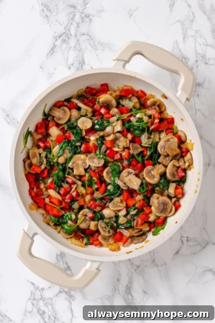 An overhead view of vibrant, mixed vegetables, including onions, bell peppers, and mushrooms, sizzling in a pan, actively sautéing.