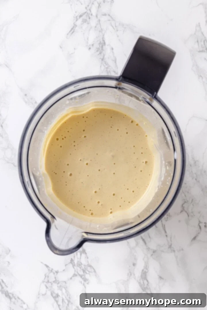 An overhead shot of a blender jar, containing a smooth and creamy tofu egg mixture, ready to be poured.