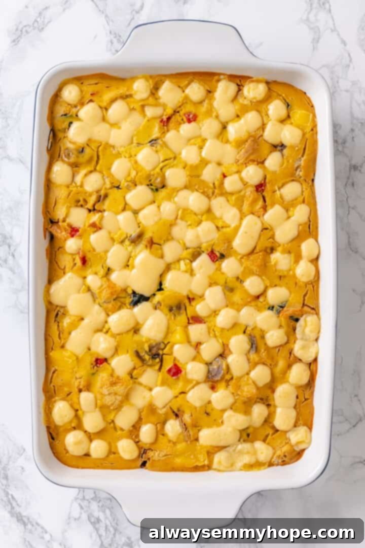 A freshly baked vegan overnight breakfast strata in a baking dish, with a golden-brown top, just out of the oven before garnishing.
