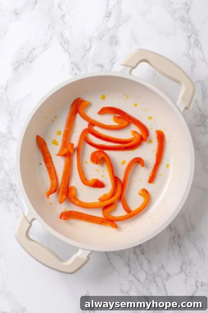 Sauté red pepper strips until softened to form the monster tongues for the sandwiches. Overhead view of red pepper strips cooking in a pan