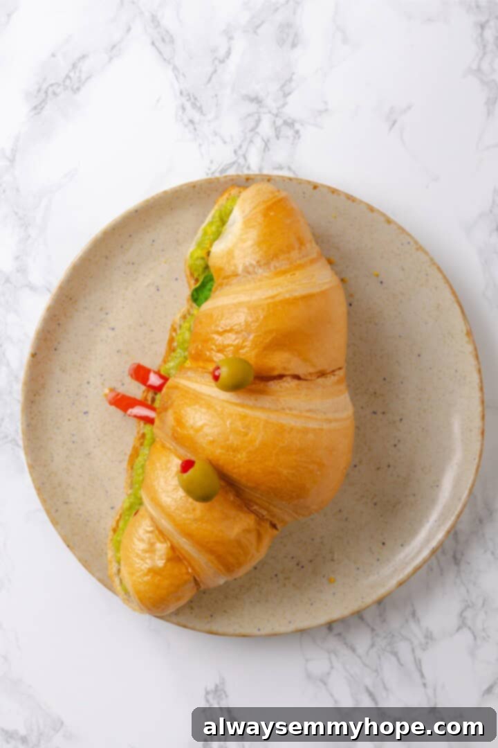 Overhead view of a finished vegan monster breakfast sandwich with olive eyes on a plate