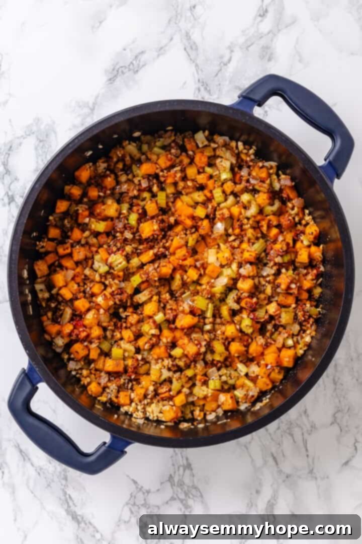 Sautéed vegetables with finely chopped walnuts, tomato paste, and Italian seasonings in a pan, releasing a fragrant aroma.