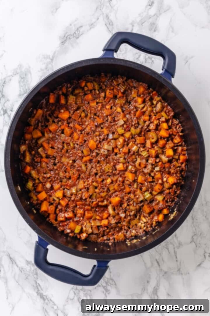 A stream of dry red wine being poured into the pot with the aromatic vegetable and walnut mixture, ready for deglazing.