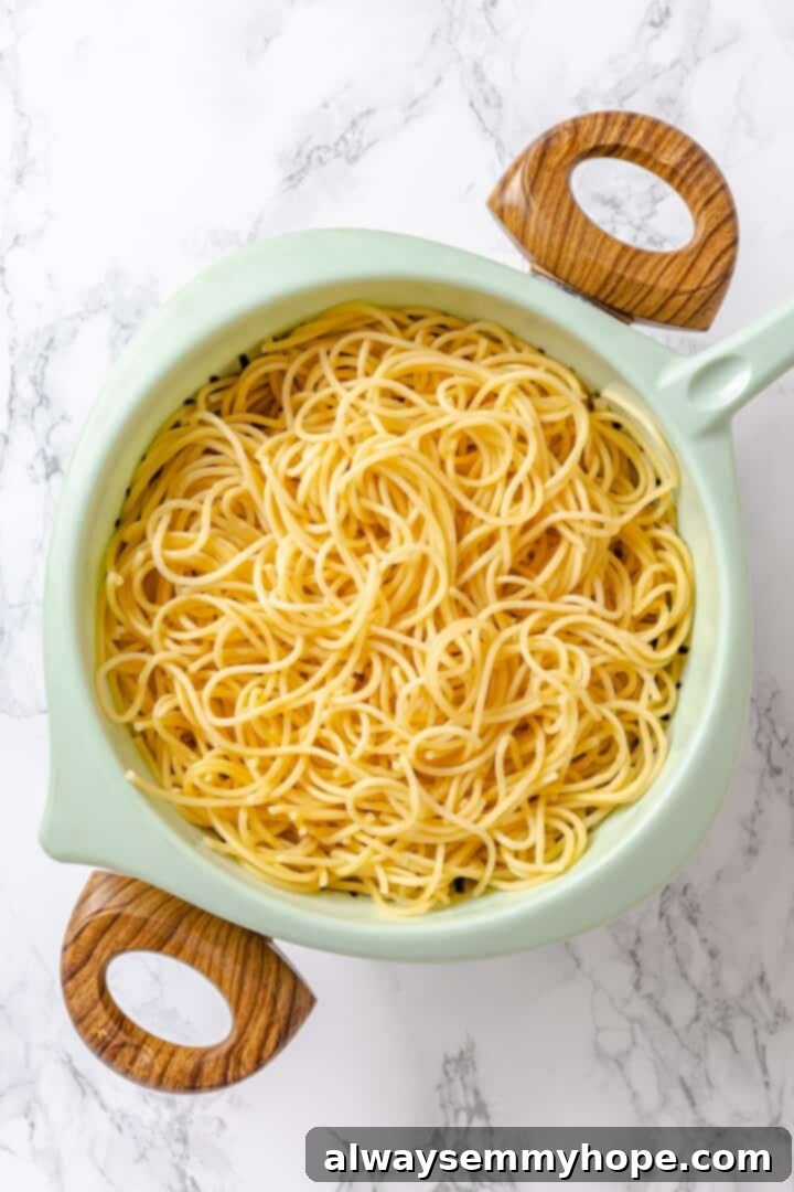 Perfectly cooked spaghetti strands draining in a colander after being boiled.