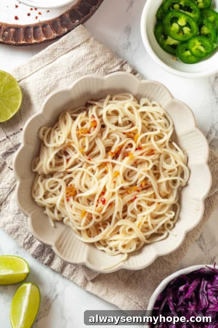 A bowl of noodles drizzled with nuoc cham sauce, topped with a colorful array of fresh vegetables and crispy tofu.