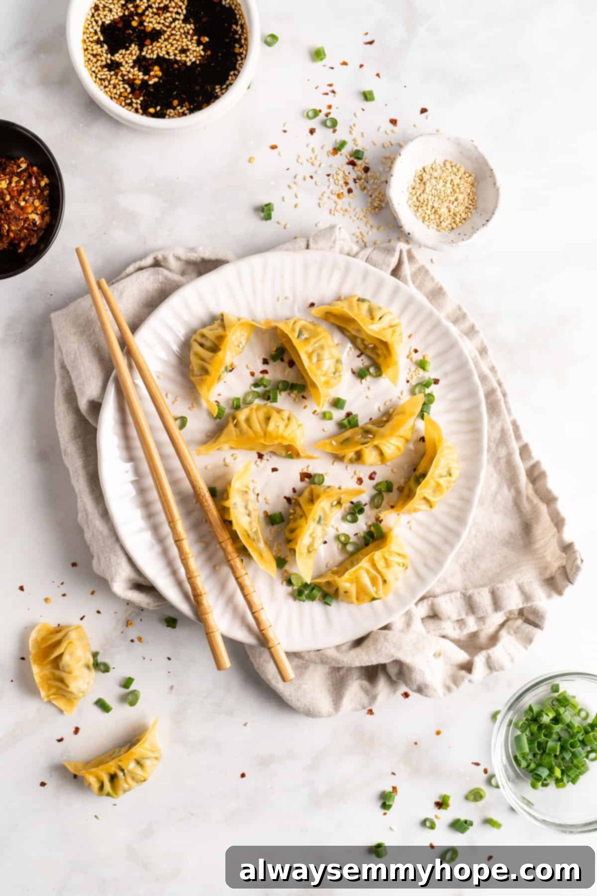 Step-by-step instructions on how to make vegan potstickers at home! These Chinese dumplings are filled with tofu and veggies. So good! Overhead view of a beautifully presented plate of vegan potstickers, surrounded by small bowls of dipping sauce, fresh herbs, and sesame seeds, highlighting a complete and inviting meal.