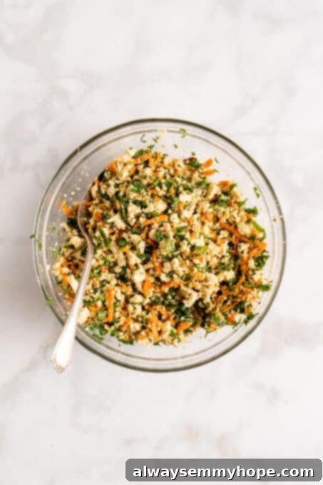 Step-by-step instructions on how to make vegan potstickers at home! These Chinese dumplings are filled with tofu and veggies. So good! Overhead view of the fully mixed vegan potsticker filling in a glass bowl, showcasing the blend of tofu, grated carrots, and green onions with a spoon ready for assembly.