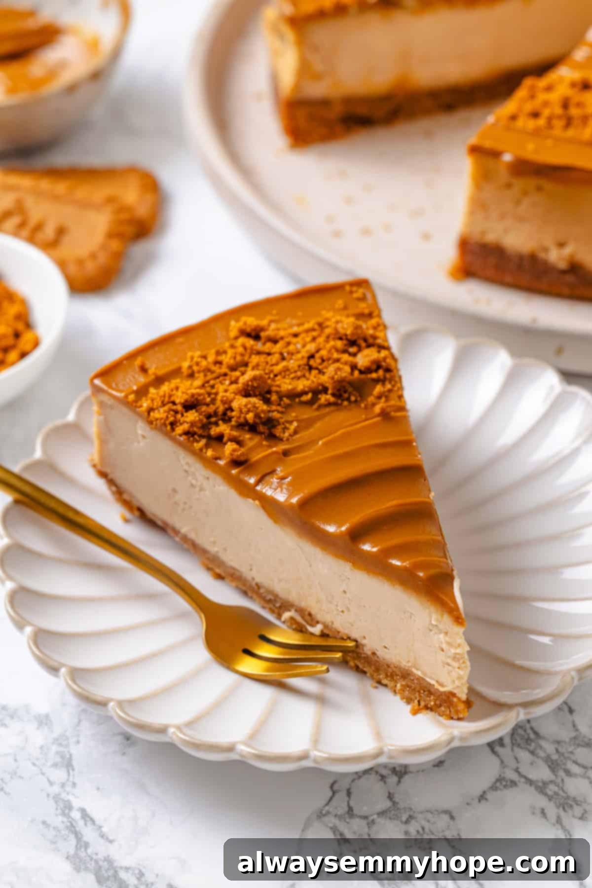 A perfectly sliced piece of vegan Biscoff cheesecake on a white plate with a fork, showcasing its luscious layers.
