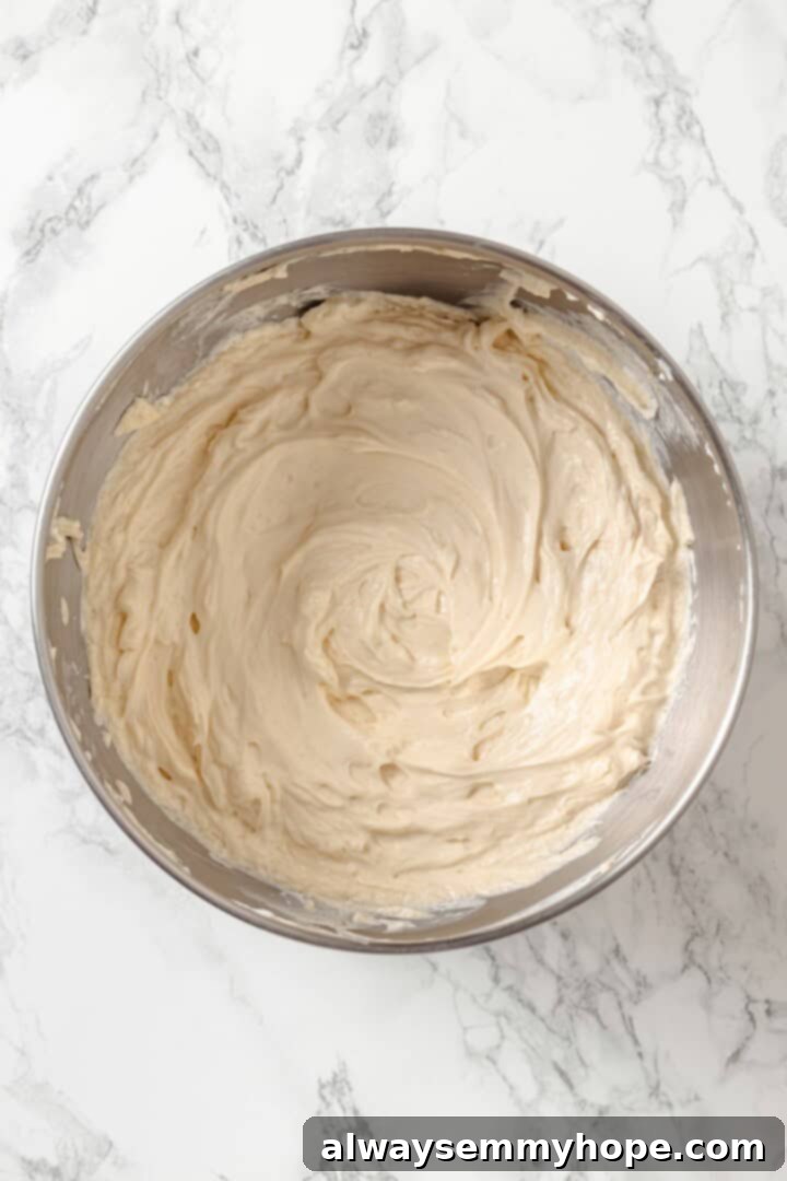 Smooth and fluffy beaten vegan cream cheese with light brown sugar in a mixing bowl.