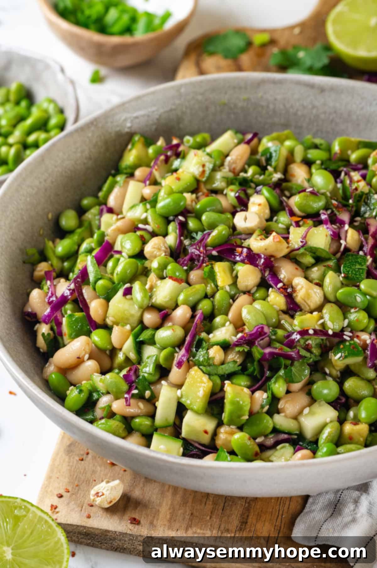 Bowl of edamame salad with a vibrant mix of green edamame, red cabbage, cucumber, and cashews.