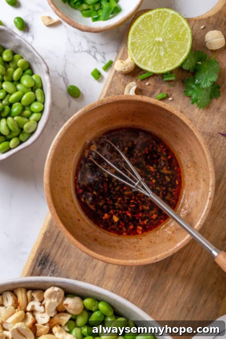 Close-up of a small bowl with ginger garlic dressing being whisked, showing a smooth, golden-brown mixture.