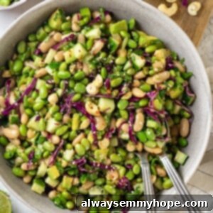 Edamame salad in bowl with two spoons.