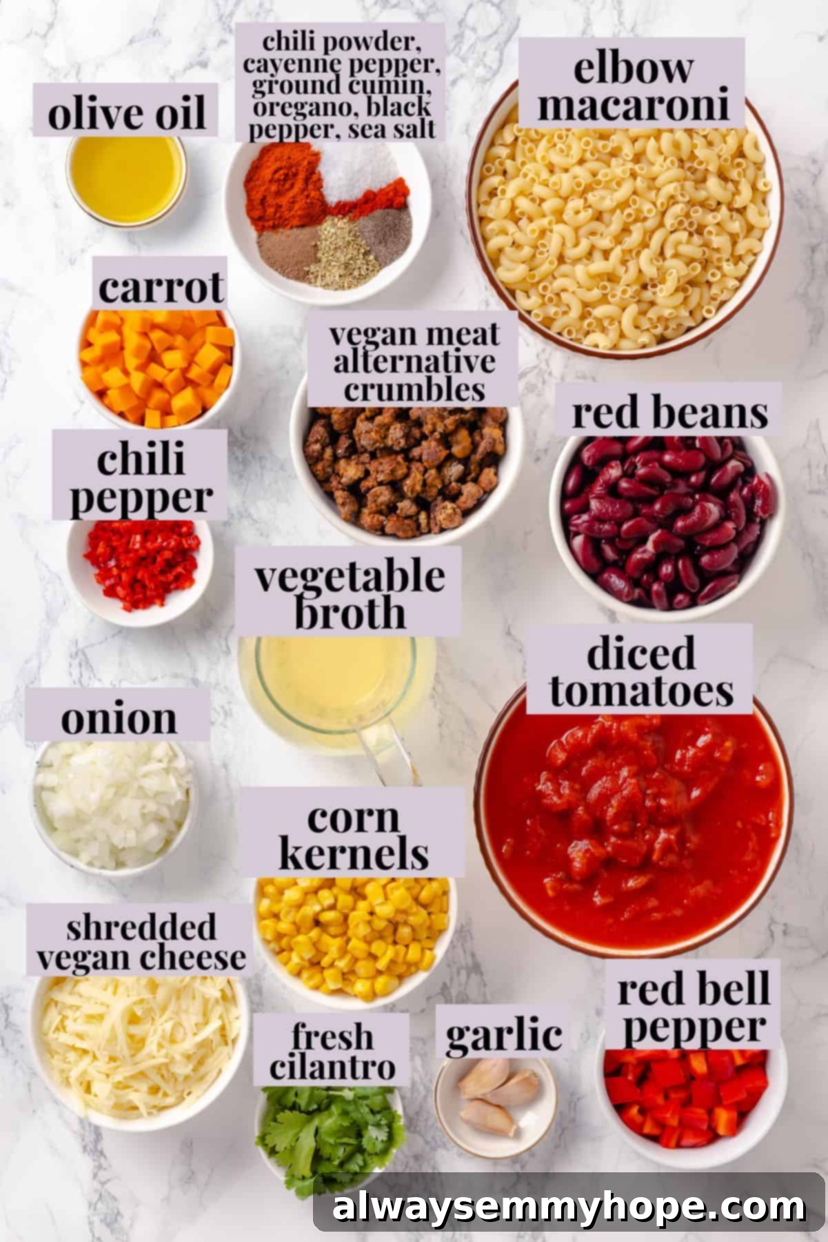 This Chili Mac and Cheese recipe is loaded with vegan ground beef, beans and lots of plant-based cheese. A kid-friendly comfort food dinner! Overhead view of various fresh ingredients for chili mac and cheese, including diced vegetables, canned goods, and seasonings, neatly arranged on a counter.