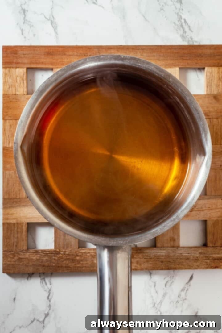 These tender cinnamon-spiced Apple Cider Donuts are baked instead of fried and made without yeast, which means they're super easy to make! Apple cider in saucepan.