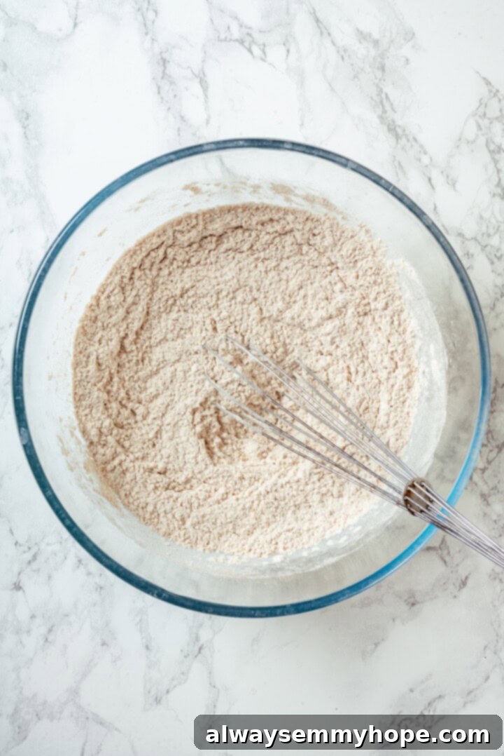These tender cinnamon-spiced Apple Cider Donuts are baked instead of fried and made without yeast, which means they're super easy to make! Dry ingredients in glass bowl with whisk.