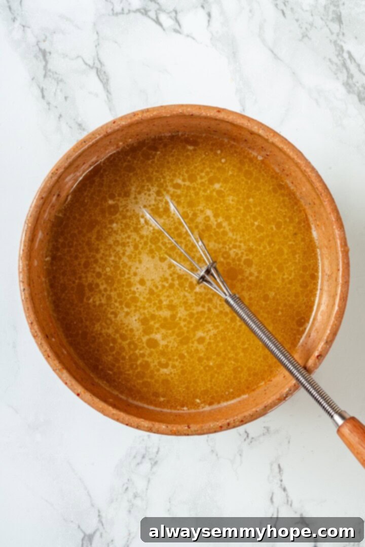These tender cinnamon-spiced Apple Cider Donuts are baked instead of fried and made without yeast, which means they're super easy to make! Melted vegan butter in bowl with whisk.