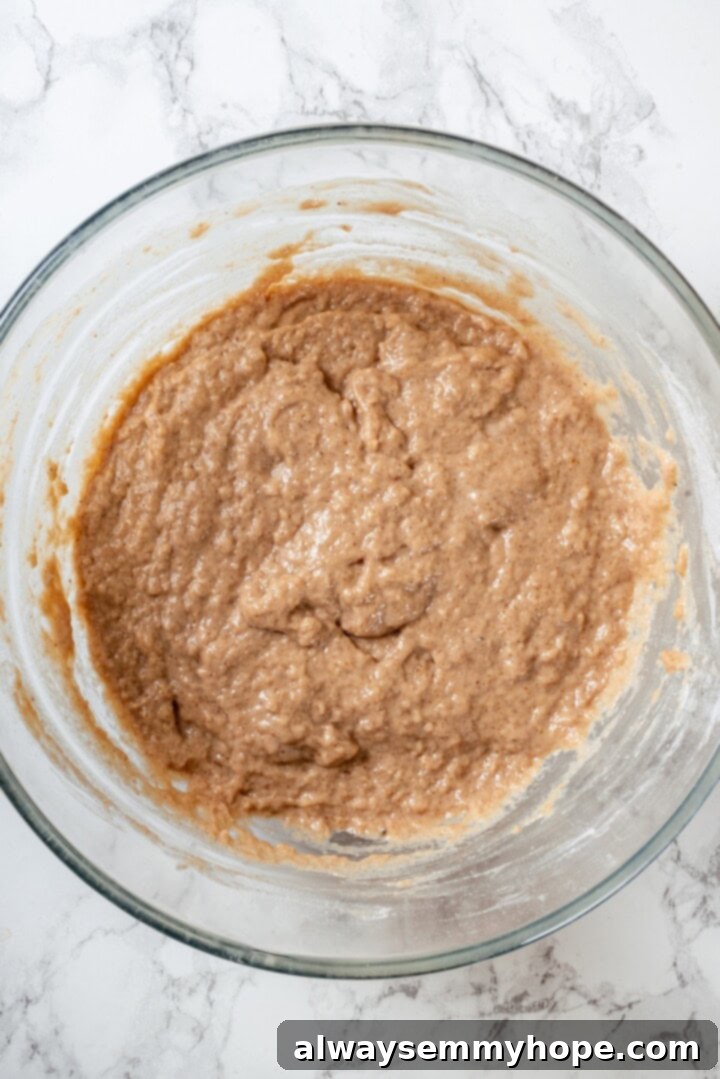 These tender cinnamon-spiced Apple Cider Donuts are baked instead of fried and made without yeast, which means they're super easy to make! Batter for vegan apple cider donuts in glass bowl.