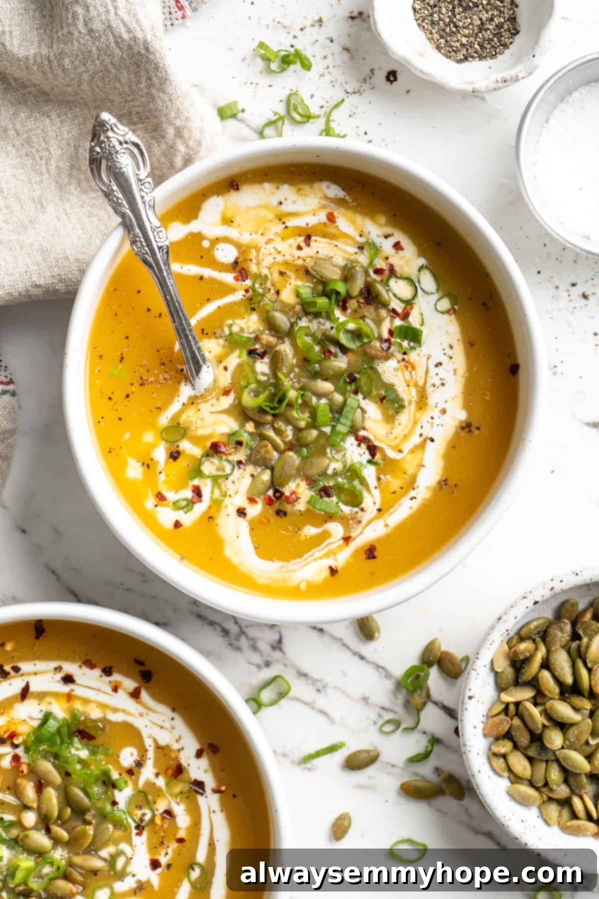 Overhead view of vegan pumpkin soup in two bowls with pepitas for garnish