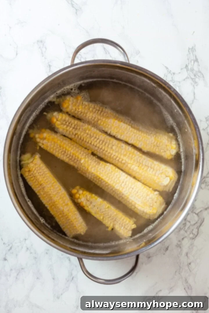 Corn cobs simmering in a pot of vegetable broth.