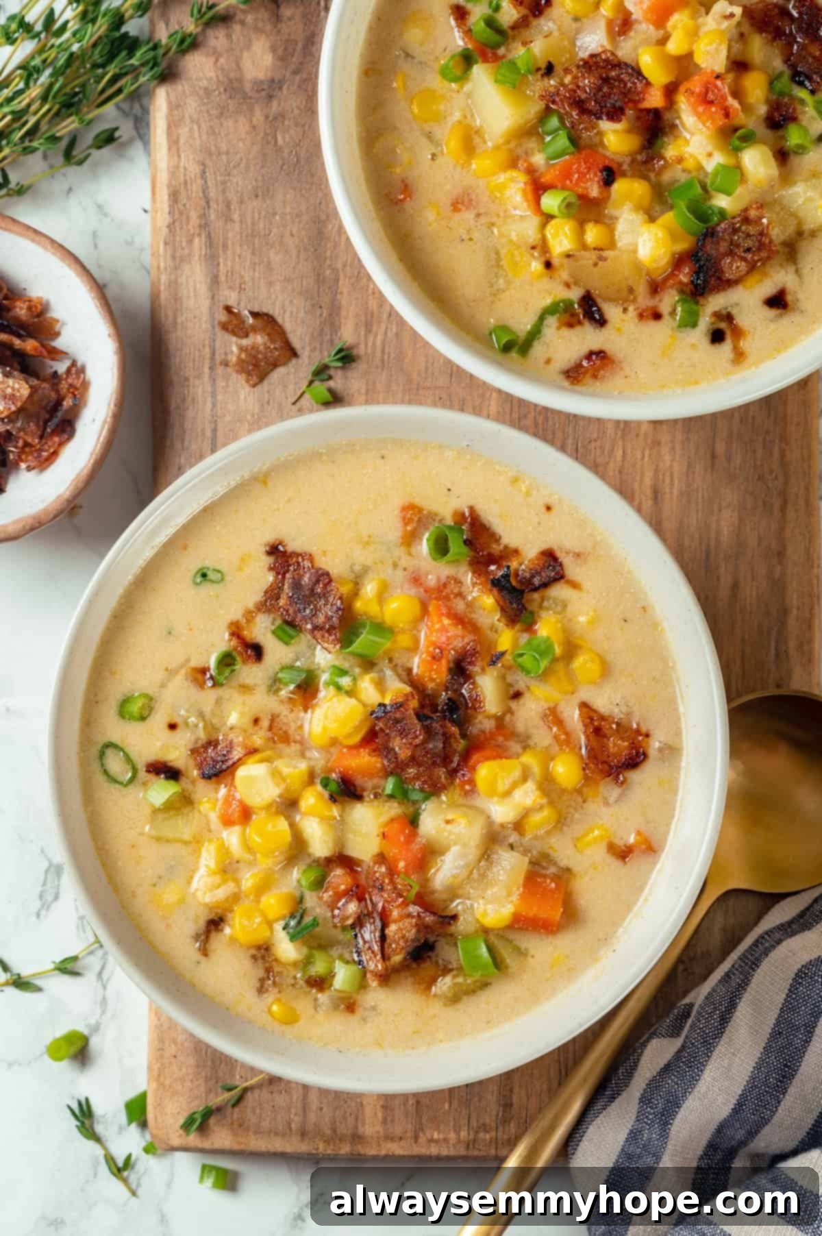 Two bowls of creamy vegan corn chowder with vegan bacon topping.