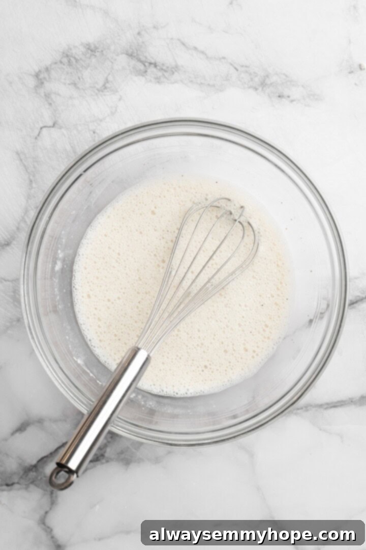 These Cauliflower Bites are crispy, crunchy and full of big flavour thanks to an irresistible sweet sriracha sauce. A total crowd pleaser! Overhead view of smooth plant milk batter mixture in a glass bowl with a whisk