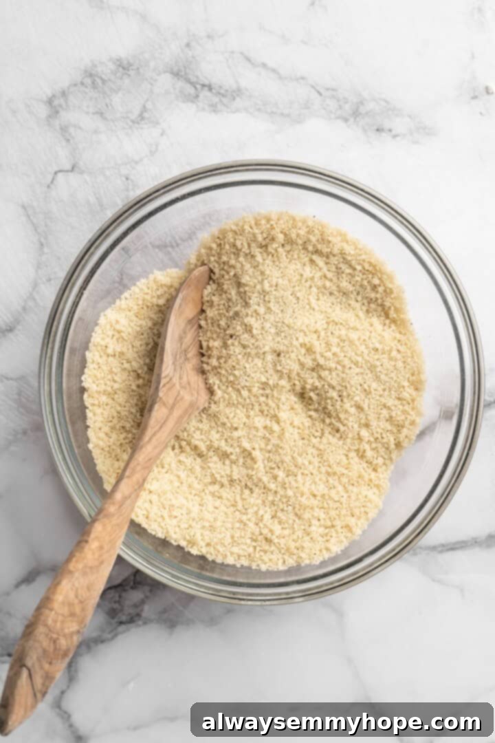 These Cauliflower Bites are crispy, crunchy and full of big flavour thanks to an irresistible sweet sriracha sauce. A total crowd pleaser! Overhead view of gluten-free breadcrumbs in a bowl with a wooden spoon, seasoned with salt and pepper