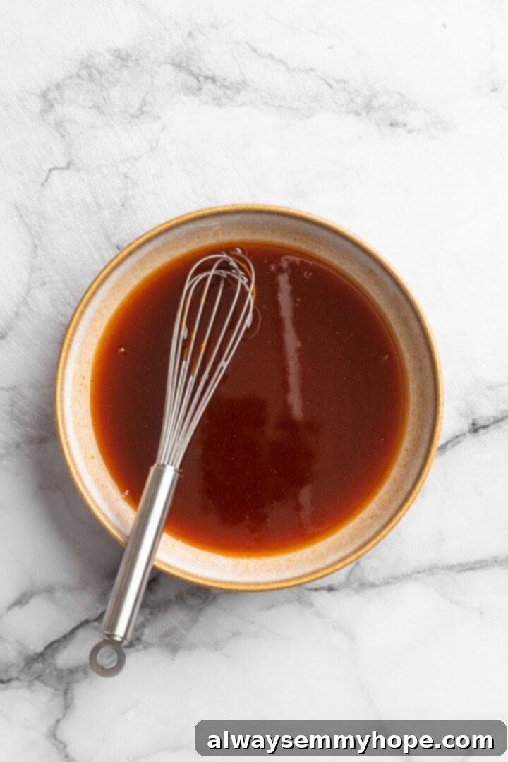 These Cauliflower Bites are crispy, crunchy and full of big flavour thanks to an irresistible sweet sriracha sauce. A total crowd pleaser! Overhead view of sweet sriracha sauce mixture in a small bowl with a whisk
