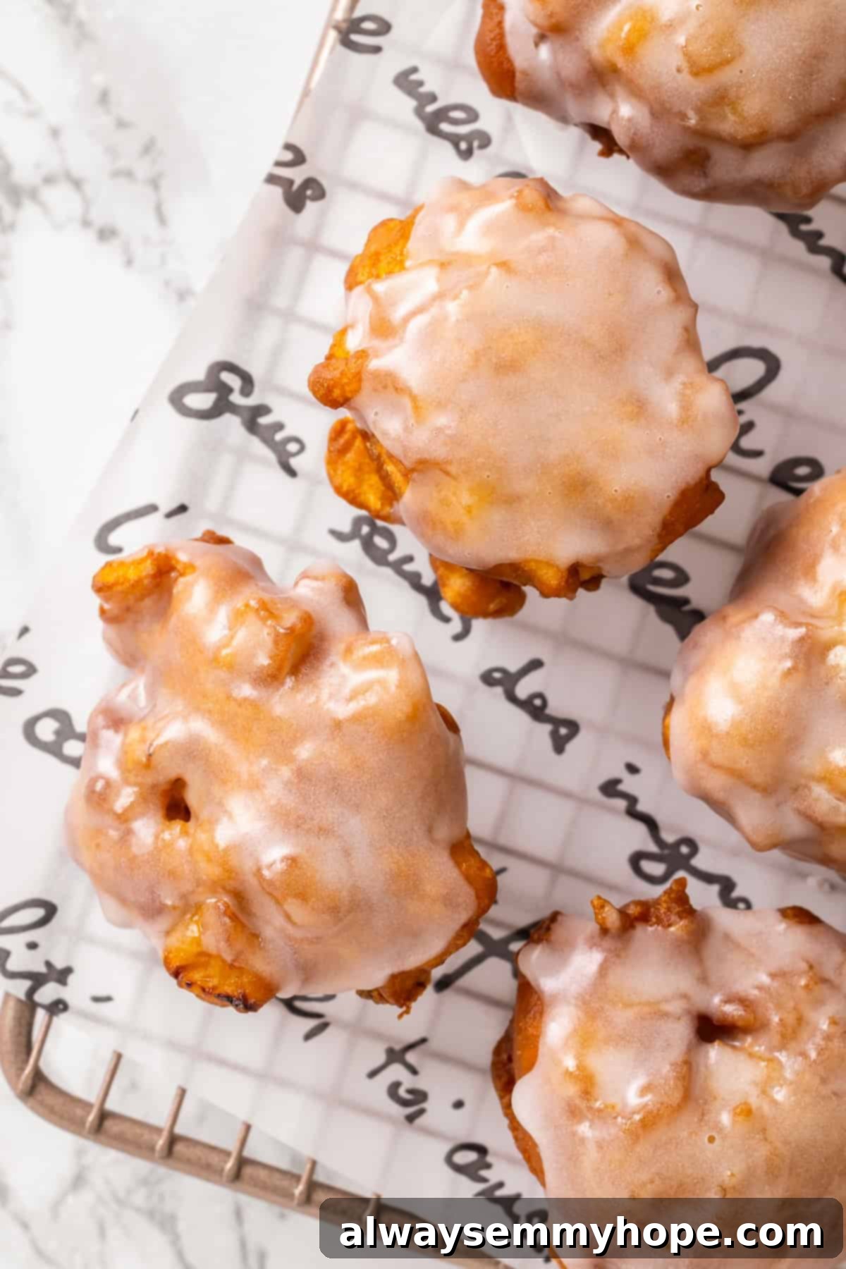 Tender apples, sticky glaze, and dough that’s crisp on the outside and pillowy soft inside make this the best vegan apple fritters recipe! Glazed vegan apple fritters on a cooling rack, glistening with glaze.