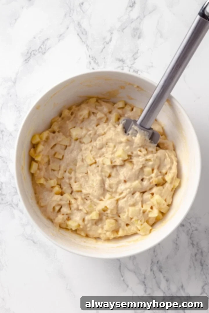 Tender apples, sticky glaze, and dough that’s crisp on the outside and pillowy soft inside make this the best vegan apple fritters recipe! Mixing bowl with vegan apple fritter dough, apples folded in.