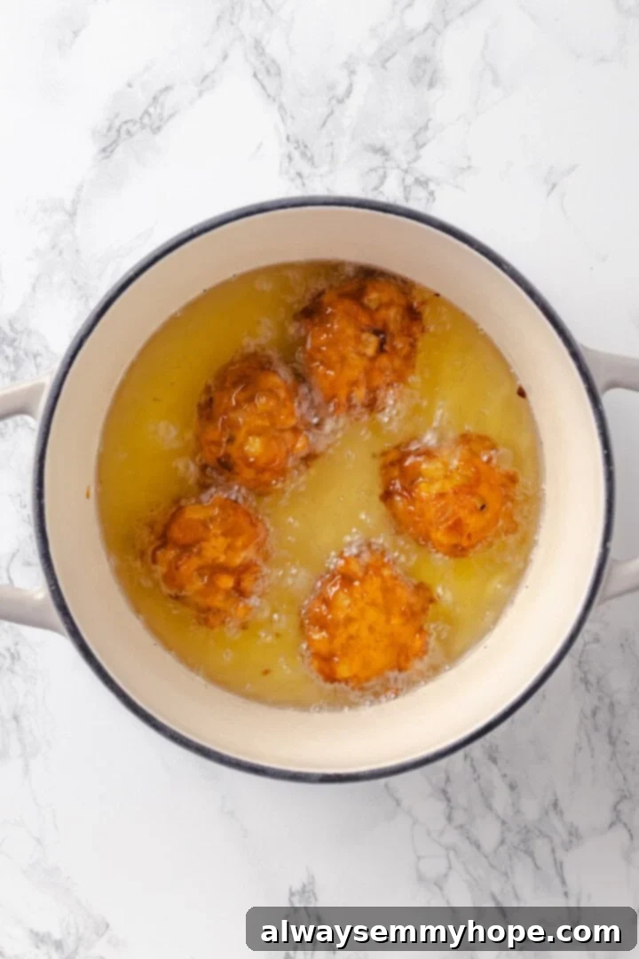 Tender apples, sticky glaze, and dough that’s crisp on the outside and pillowy soft inside make this the best vegan apple fritters recipe! Vegan apple fritters frying in hot oil in a pot.