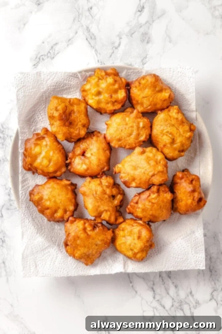 Tender apples, sticky glaze, and dough that’s crisp on the outside and pillowy soft inside make this the best vegan apple fritters recipe! Fried vegan apple fritters draining on a paper towel-lined plate.