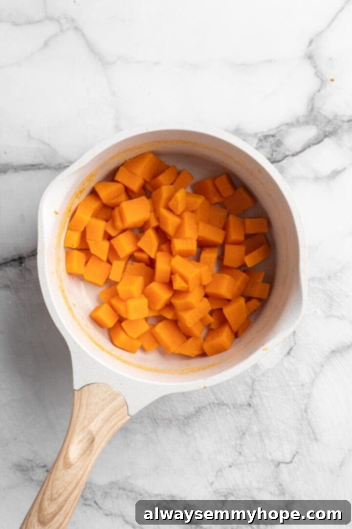 Boil Sweet Potatoes for a Creamy Pizza Base Cooked sweet potato cubes in a pan after boiling, tender and ready for mashing to create the creamy pizza sauce.
