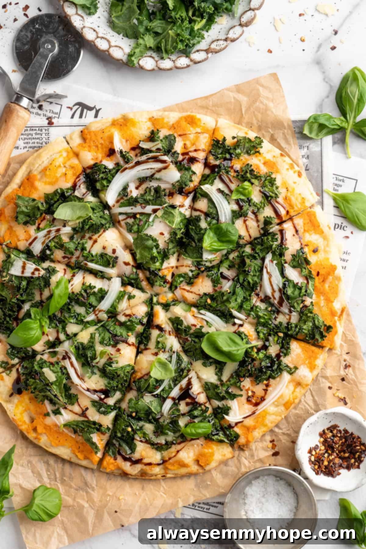 Enjoy a Slice of Vegan Sweet Potato and Kale Pizza with Balsamic Glaze Overhead view of a beautifully sliced sweet potato and kale pizza, glistening with a shiny balsamic glaze finish, ready to be served.
