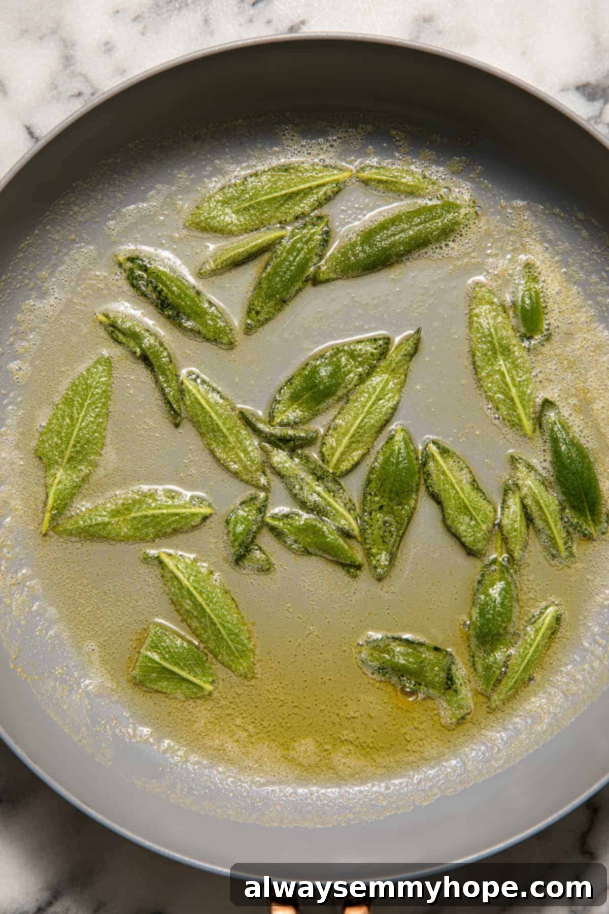 Fresh sage leaves sizzling in hot vegan butter or coconut oil in a pan.