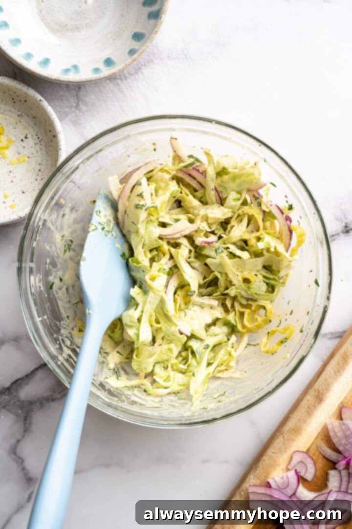 Stirring grinder slaw in glass bowl.