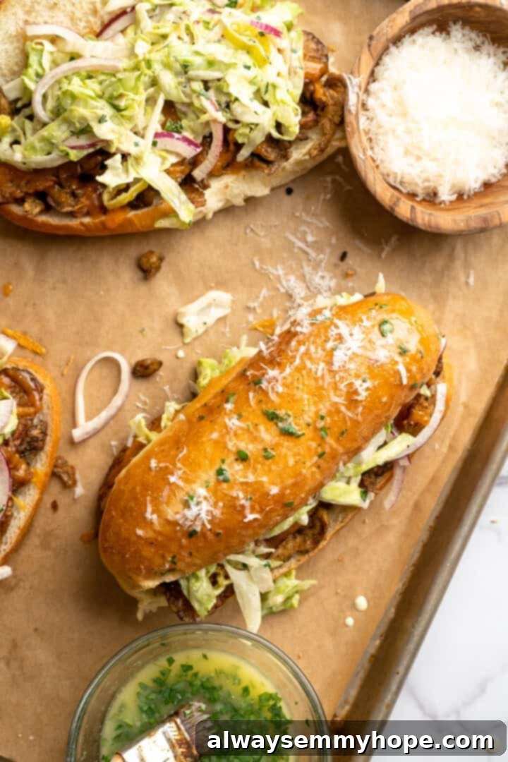 Assembled vegan grinder sandwich with bowl of Parmesan and bowl of herbed butter.