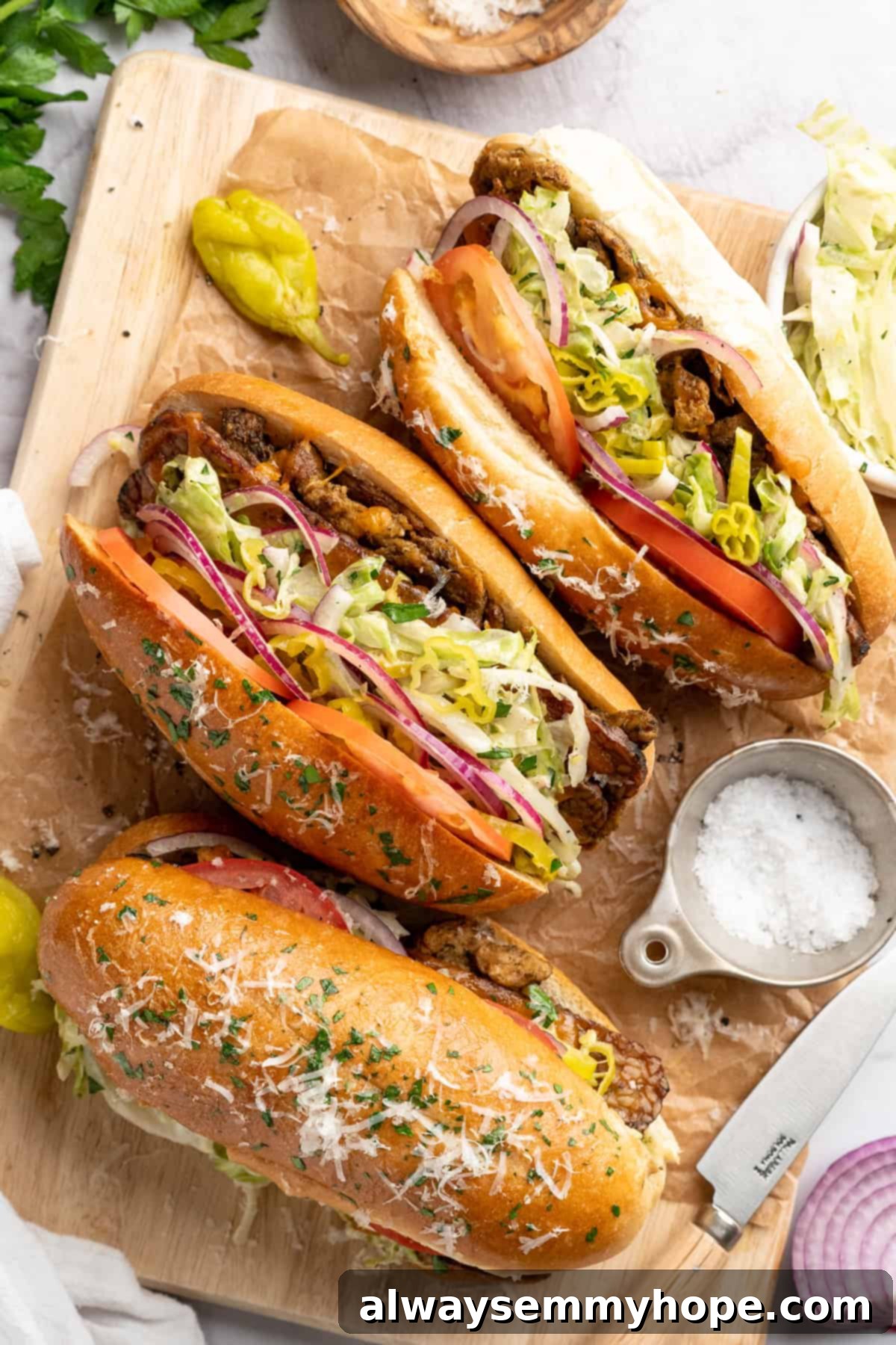 Three vegan grinder sandwiches on parchment-lined cutting board.
