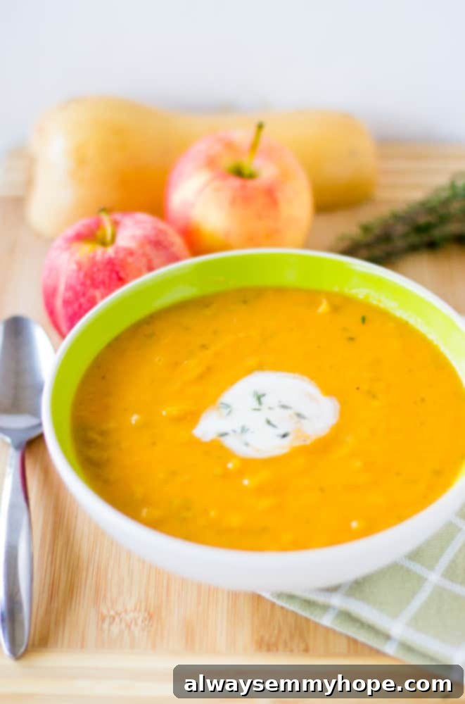 A beautifully presented bowl of creamy Vegan Butternut Squash and Apple Soup, garnished with a swirl of coconut cream and fresh herbs.