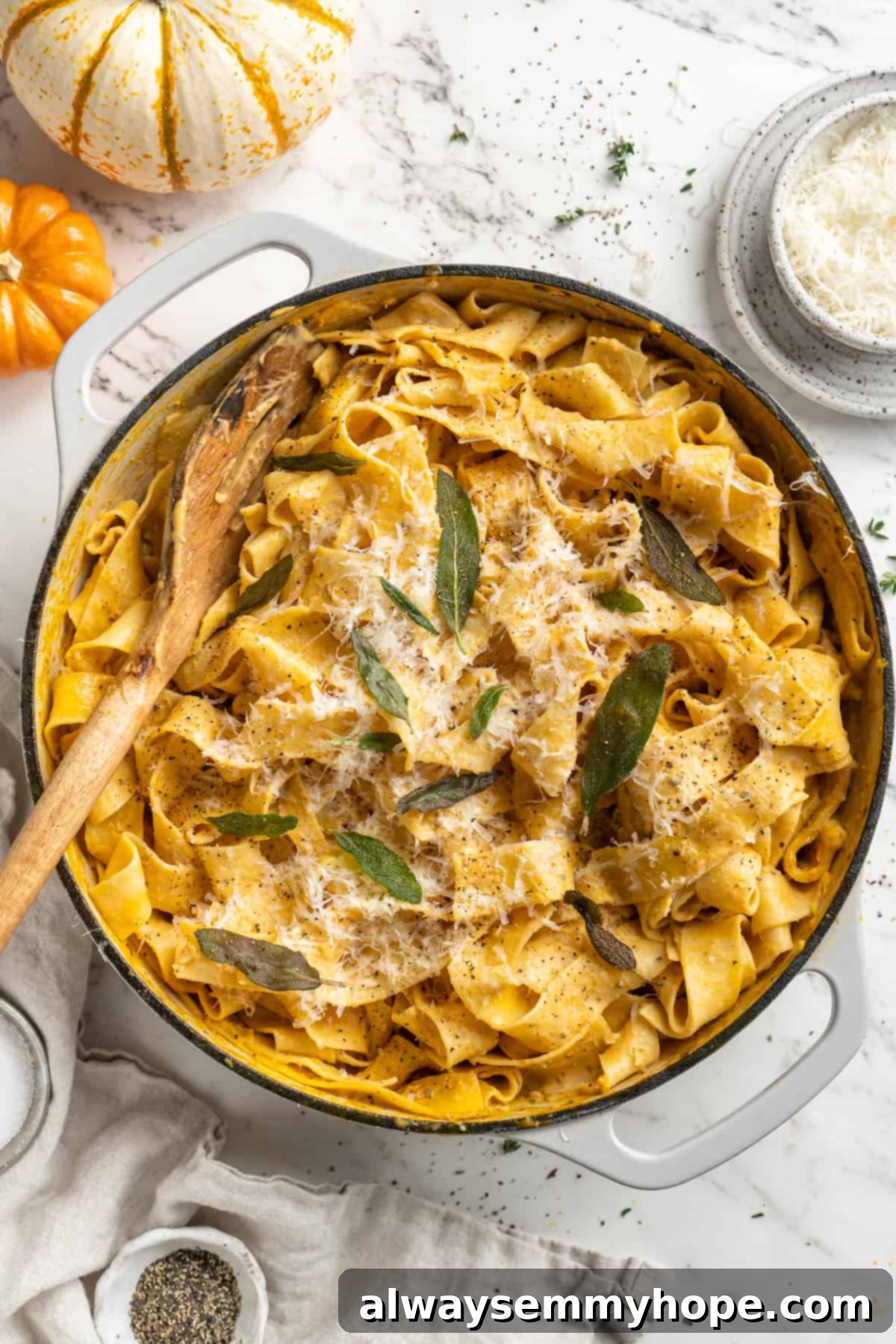 This easy pumpkin Alfredo pasta is rich, creamy, and perfect for a weeknight. Turn simple pantry ingredients into a restaurant-style meal! Overhead view of pumpkin alfredo pasta in skillet garnished with sage leaves and parmesan