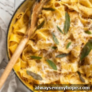 Velvety Pumpkin Alfredo Pasta 2 Overhead view of pumpkin alfredo pasta in skillet with wooden spoon and crispy sage leaf garnish