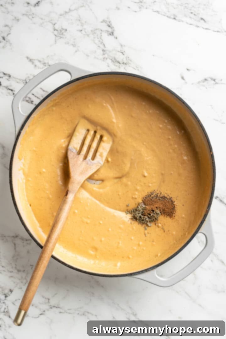 This easy pumpkin Alfredo pasta is rich, creamy, and perfect for a weeknight. Turn simple pantry ingredients into a restaurant-style meal! Overhead view of spices and herbs added to skillet of pumpkin alfredo sauce