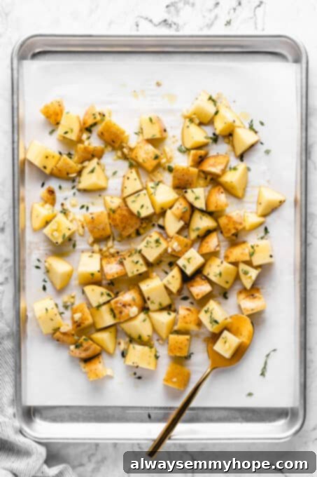 Bake. ingredients for garlic roasted potatoes spread evenly on a lined cookie sheet, ready for baking
