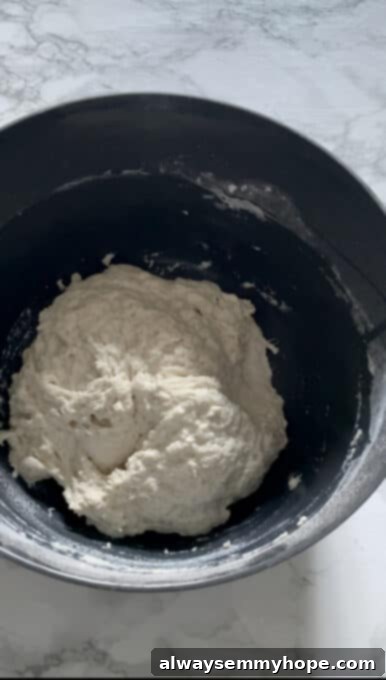 The shaggy, wet dough of focaccia bread inside a mixing bowl after initial mixing.