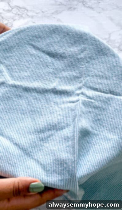 A mixing bowl containing focaccia dough, covered with a blue kitchen towel, indicating the start of the rising process.