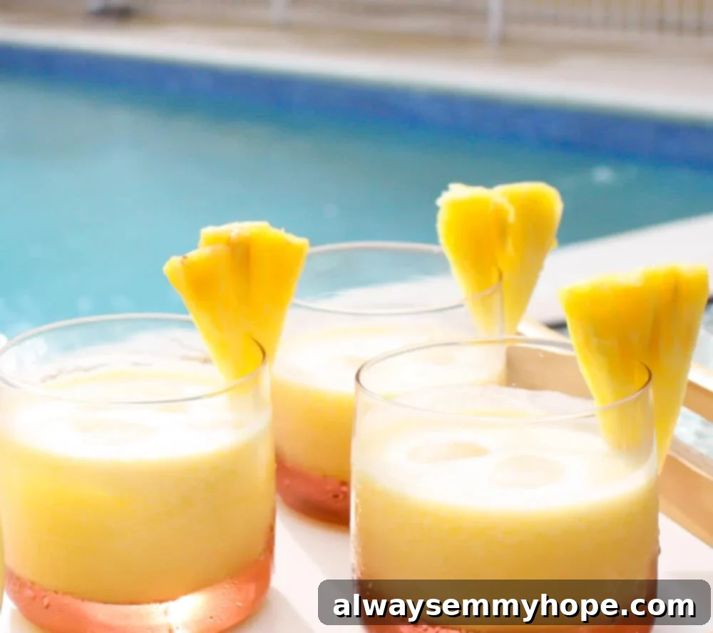 Three glasses of vibrant pineapple coconut rum cocktails served by a sparkling blue pool, garnished with fresh pineapple wedges.