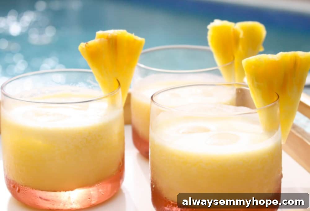 A refreshing pineapple coconut rum cocktail, perfectly garnished, sits by the edge of a swimming pool on a sunny day.
