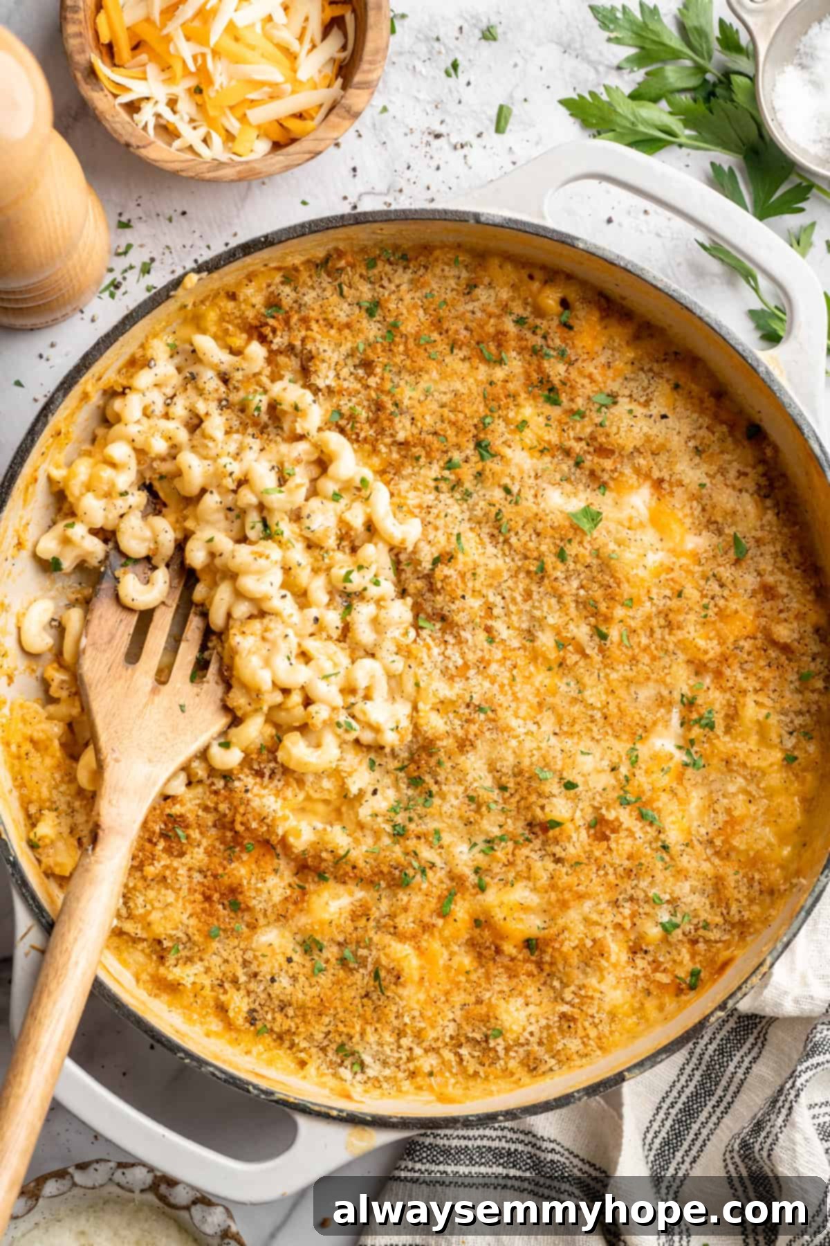 A wooden spatula lifting a scoop of perfectly golden and creamy 3-Cheese Vegan Mac and Cheese from a hot skillet, showcasing its rich texture and inviting warmth.