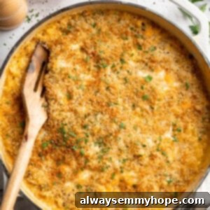 Wooden spatula digging into a skillet of hot, bubbly 3-Cheese Vegan Mac and Cheese, ready to be served.