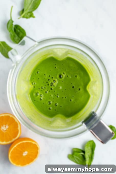 This vegan green smoothie only has four ingredients and is one of my favourite quick, easy breakfasts. It's smooth and creamy without dairy! Overhead view of a perfectly blended vegan green smoothie inside the blender, showing a smooth and creamy texture.