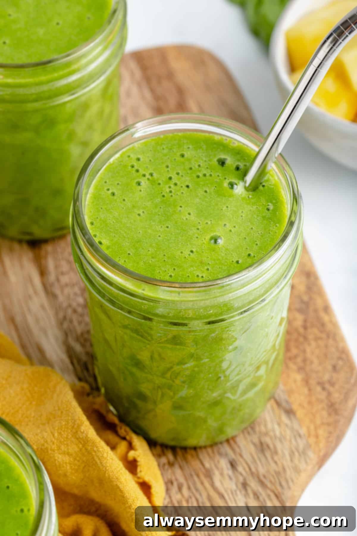 This vegan green smoothie only has four ingredients and is one of my favourite quick, easy breakfasts. It's smooth and creamy without dairy! Green Smoothie in glass with a straw sticking out, ready to be enjoyed.